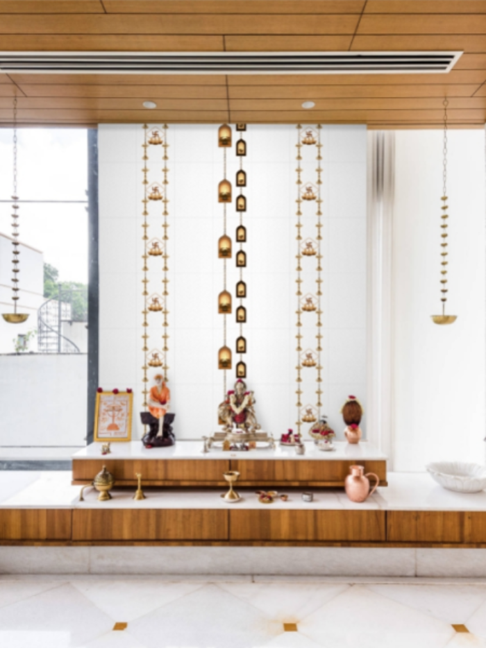 Decorative wall with hanging gold ornaments and a small statue in a modern interior setting.
