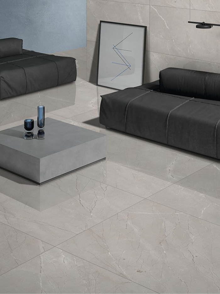 Modern living room with gray tiles, black sofa, and abstract art.