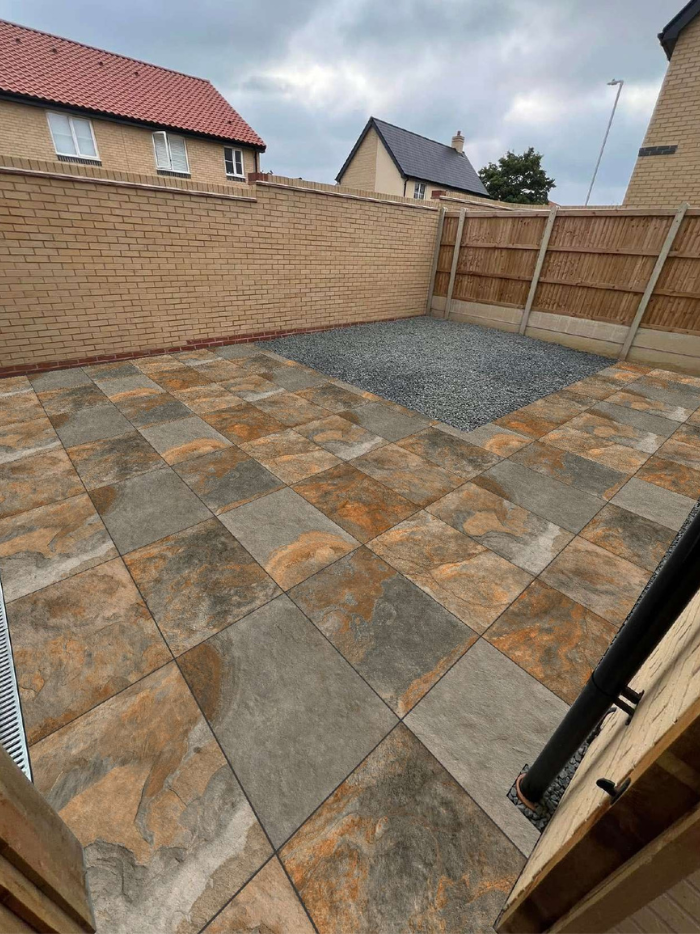 Paved patio area with a wooden fence and house in the background