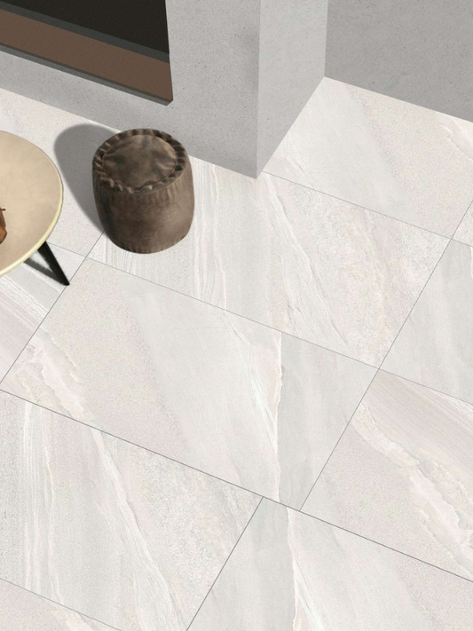 White marble tiles on a floor with a small round stool and table.