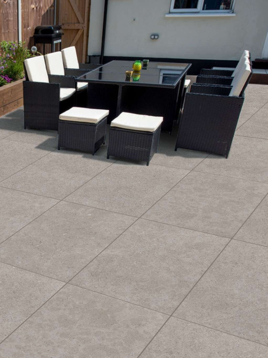 Outdoor patio set with black furniture and white cushions on a tiled patio.