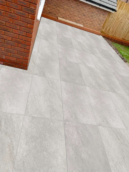 Gray tiled pavement next to a brick wall