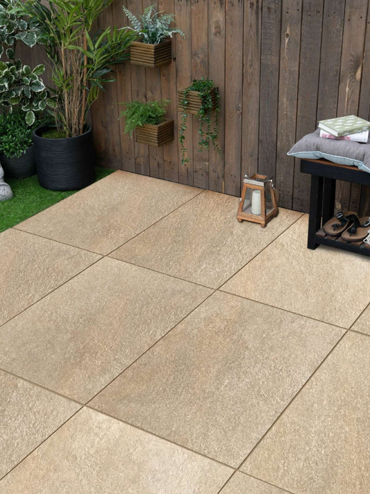 Beige patio tiles in an outdoor setting with plants and a wooden wall.