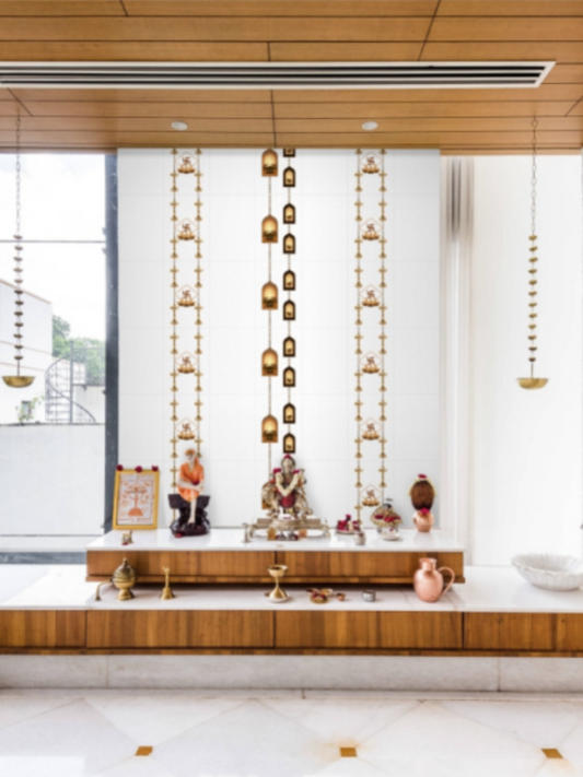 Decorative wall with hanging gold ornaments and a small statue in a modern interior setting.