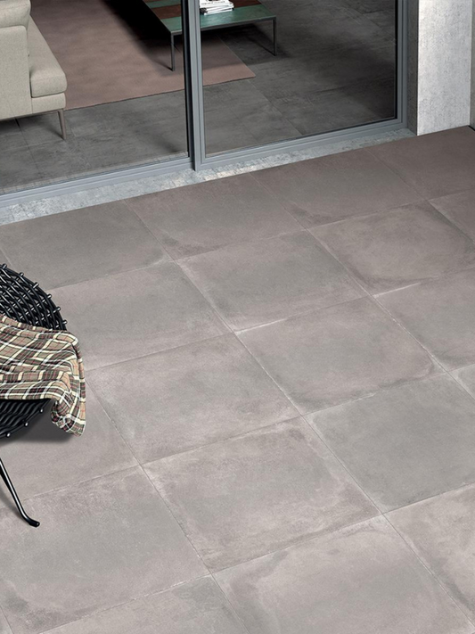 Gray tiles on a floor with a chair and table in the background