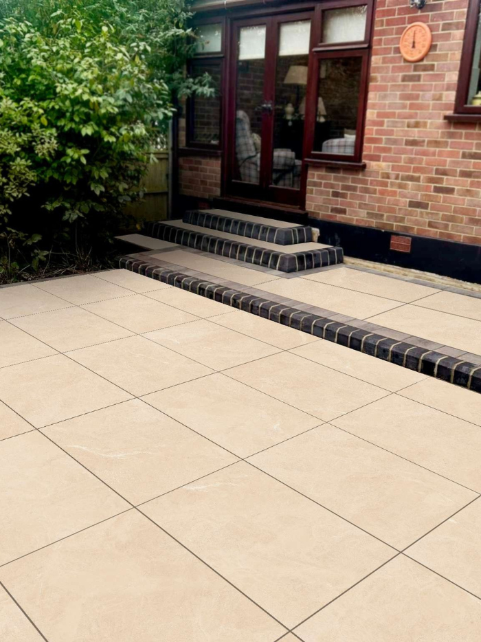Beige patio with black steps leading to a brick building